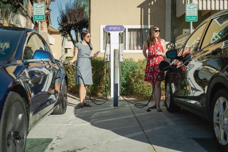 Two women charging electric vehicles